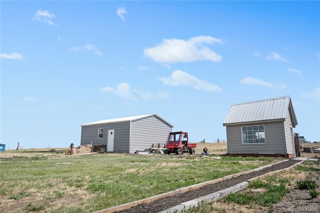 exterior space featuring a yard, metal roof, and an outdoor structure