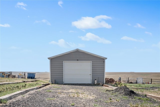 detached garage featuring gravel driveway and a rural view