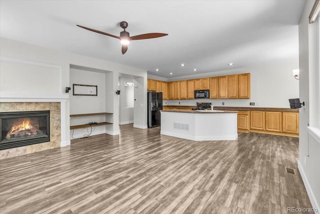 2142 Paint Pony Cir, Castle Rock, CO 80108 - kitchen featuring recessed lighting, open floor plan, black appliances, light wood finished floors, and a tiled fireplace