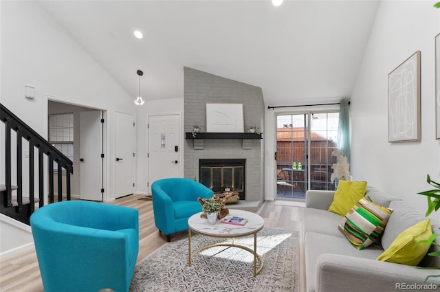 living room featuring a brick fireplace, high vaulted ceiling, and light wood-type flooring