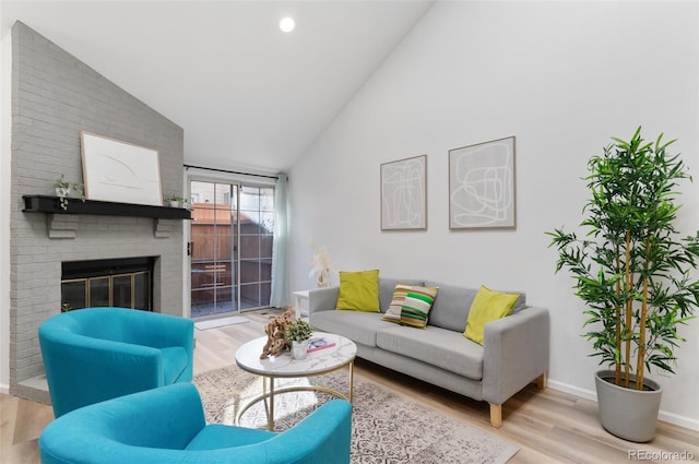 living room with a brick fireplace, vaulted ceiling, and light hardwood / wood-style floors