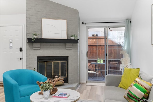 living room featuring lofted ceiling, a fireplace, and light hardwood / wood-style flooring