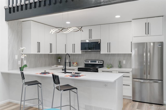 kitchen with hanging light fixtures, stainless steel appliances, and white cabinets