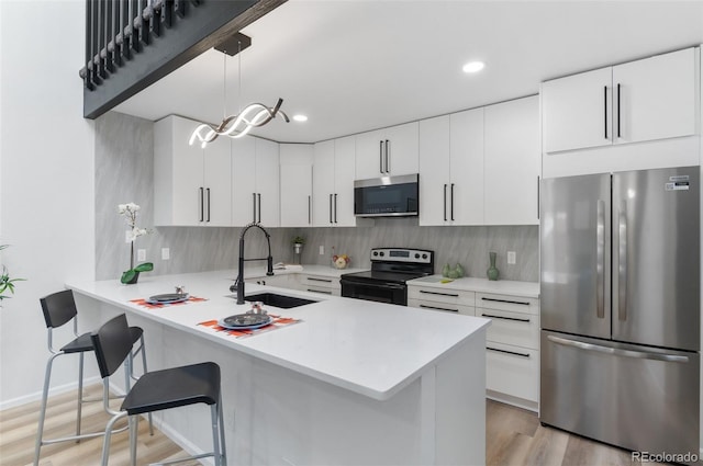 kitchen featuring pendant lighting, white cabinetry, stainless steel appliances, and kitchen peninsula