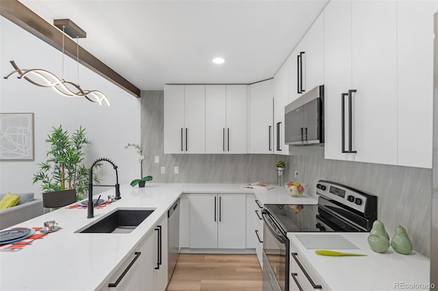 kitchen featuring appliances with stainless steel finishes, decorative light fixtures, sink, and white cabinets