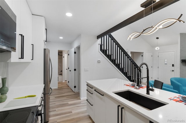 kitchen featuring white cabinetry, sink, decorative light fixtures, and stainless steel appliances