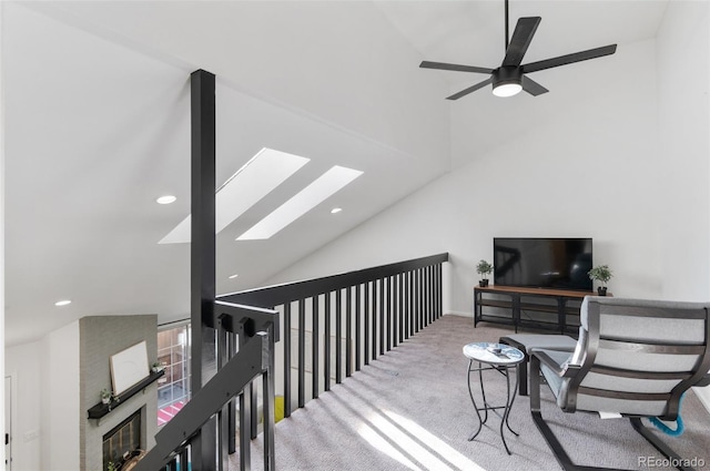 interior space featuring ceiling fan, vaulted ceiling with skylight, and carpet