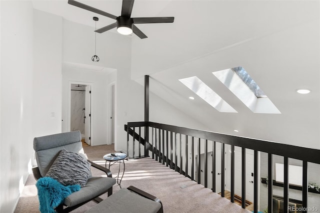 corridor featuring a skylight, high vaulted ceiling, and carpet