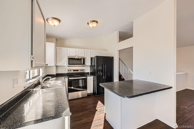 kitchen featuring kitchen peninsula, stainless steel appliances, lofted ceiling, white cabinetry, and sink