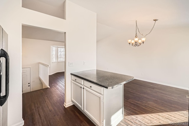 kitchen with dark wood-type flooring, white cabinetry, an inviting chandelier, and decorative light fixtures