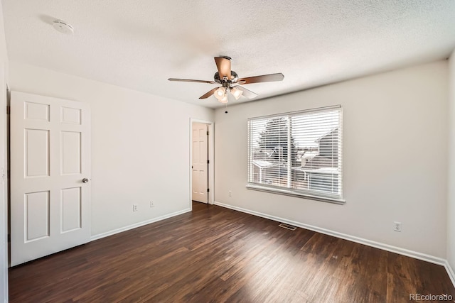 spare room with a textured ceiling, ceiling fan, and dark hardwood / wood-style flooring