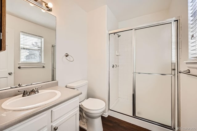 bathroom with a shower with door, hardwood / wood-style floors, vanity, and toilet