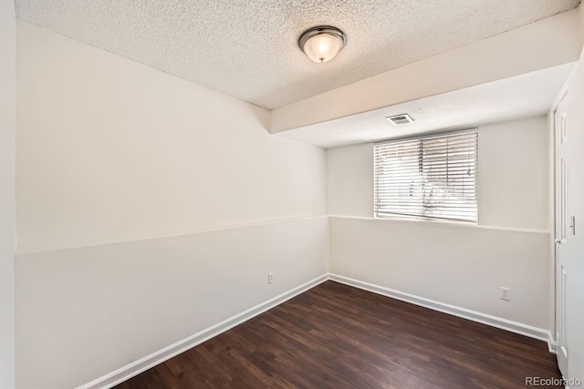 empty room with a textured ceiling and dark hardwood / wood-style floors