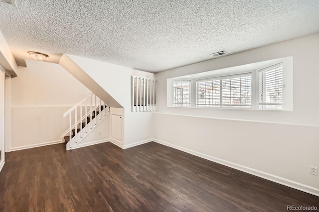 empty room with a textured ceiling and dark hardwood / wood-style floors