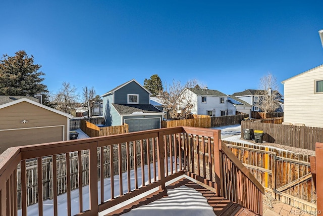 snow covered deck featuring a garage and an outbuilding