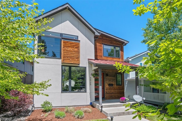 modern home featuring covered porch, metal roof, a standing seam roof, and stucco siding