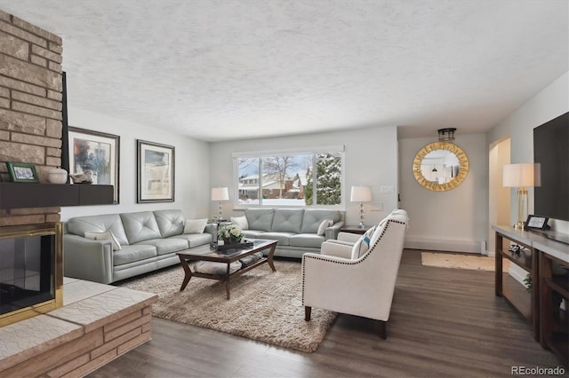 living room featuring a brick fireplace, dark hardwood / wood-style floors, and a textured ceiling