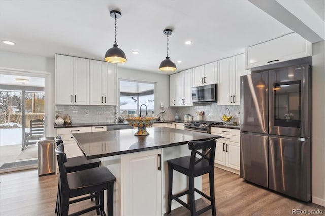 kitchen with white cabinetry, a kitchen breakfast bar, a center island, and appliances with stainless steel finishes