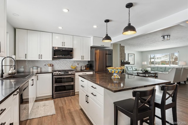 kitchen featuring pendant lighting, sink, a breakfast bar area, white cabinetry, and stainless steel appliances