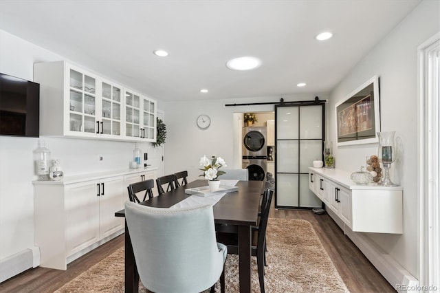 dining room featuring dark wood-type flooring, stacked washer and dryer, and a barn door