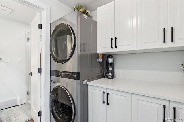 laundry area featuring stacked washer / drying machine and cabinets