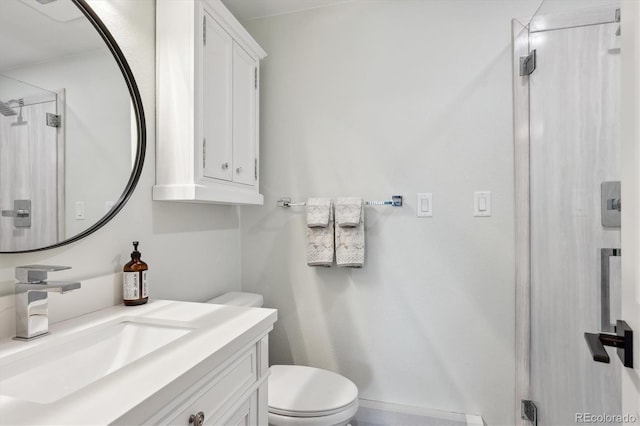 bathroom with vanity, a shower with door, and toilet