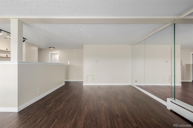 spare room with a baseboard radiator, dark hardwood / wood-style floors, and a textured ceiling