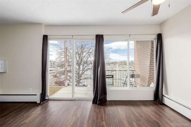 spare room featuring ceiling fan, dark wood-type flooring, and baseboard heating