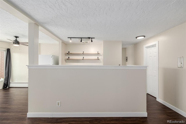 kitchen with white refrigerator, a baseboard heating unit, ceiling fan, dark wood-type flooring, and a textured ceiling