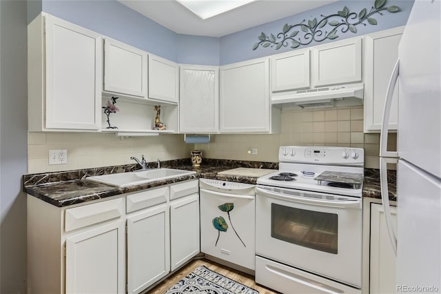 kitchen featuring sink, white appliances, white cabinetry, dark stone countertops, and decorative backsplash