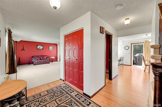 entryway with baseboard heating, a textured ceiling, baseboards, and light wood-type flooring