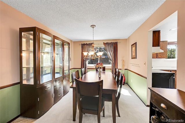 dining space with light colored carpet, a textured ceiling, and an inviting chandelier
