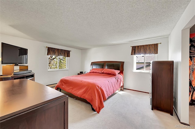 bedroom with baseboards, baseboard heating, a textured ceiling, and light colored carpet