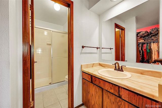 full bath featuring a walk in closet, vanity, toilet, tile patterned floors, and a shower stall