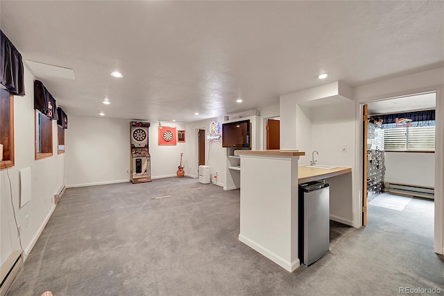 kitchen with a sink, baseboard heating, recessed lighting, and freestanding refrigerator