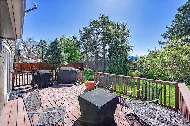 wooden deck featuring a fenced backyard, a yard, and grilling area