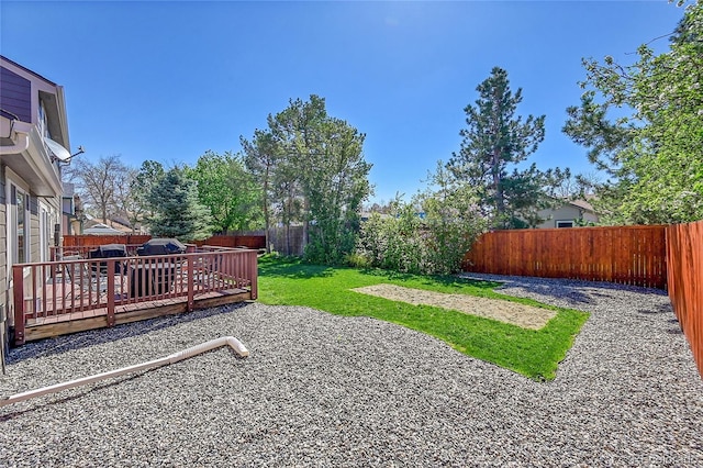 view of yard with a fenced backyard, a wooden deck, and a patio area