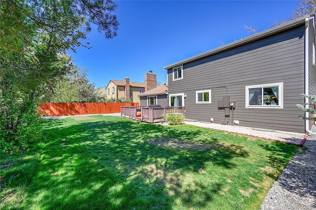 rear view of property with a yard, a deck, and fence