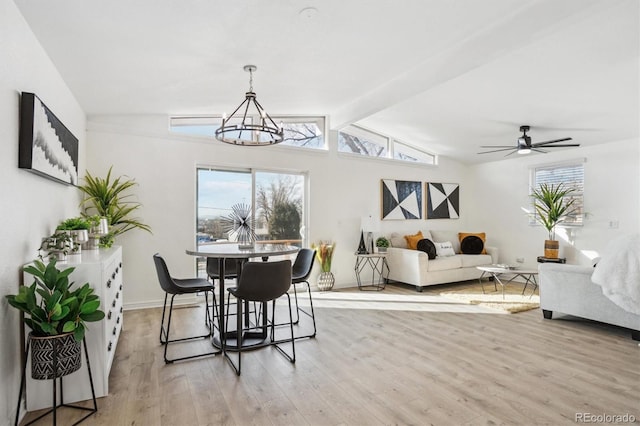 dining area with vaulted ceiling with beams, light wood-style flooring, baseboards, and ceiling fan with notable chandelier