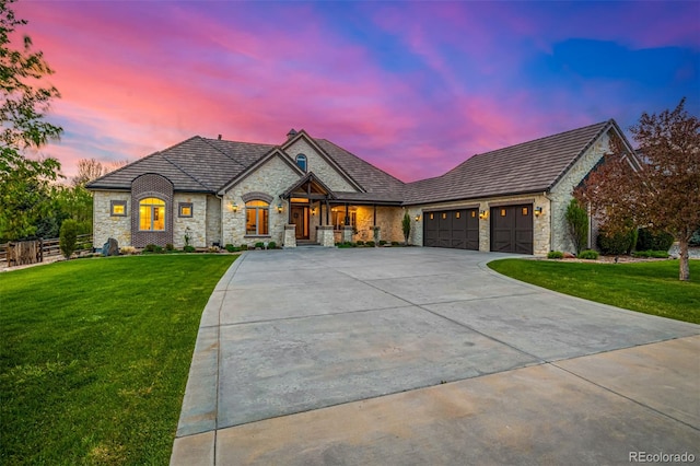 french country home with a garage and a lawn