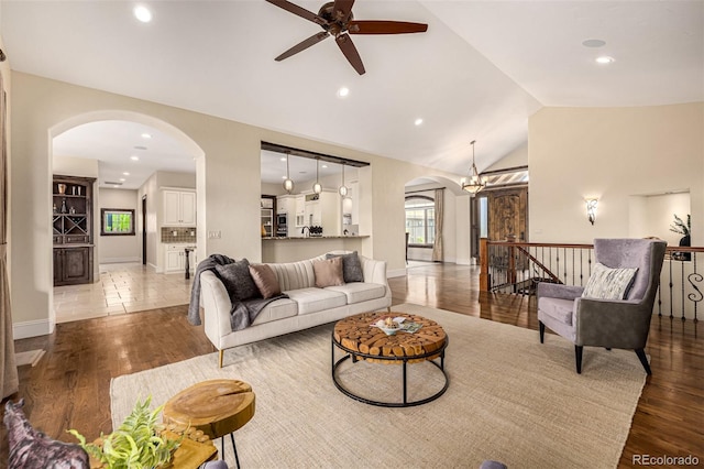 living room featuring lofted ceiling, light hardwood / wood-style floors, and ceiling fan with notable chandelier