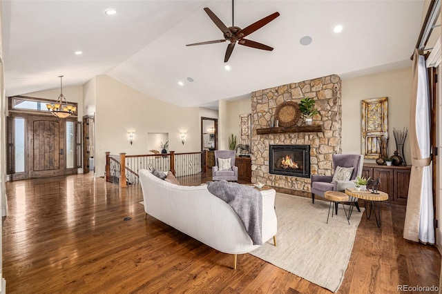 living room featuring high vaulted ceiling, ceiling fan, a stone fireplace, and dark hardwood / wood-style floors