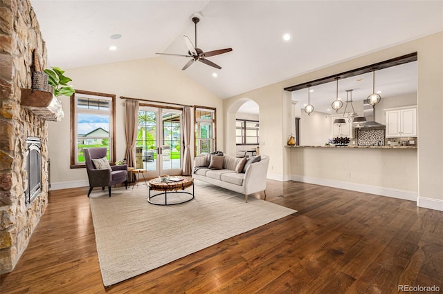 living room with ceiling fan, a fireplace, dark wood-type flooring, lofted ceiling, and french doors