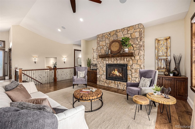 living room featuring wood-type flooring, ceiling fan, lofted ceiling, and a stone fireplace