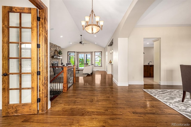 foyer entrance featuring ceiling fan with notable chandelier, vaulted ceiling, and dark hardwood / wood-style flooring