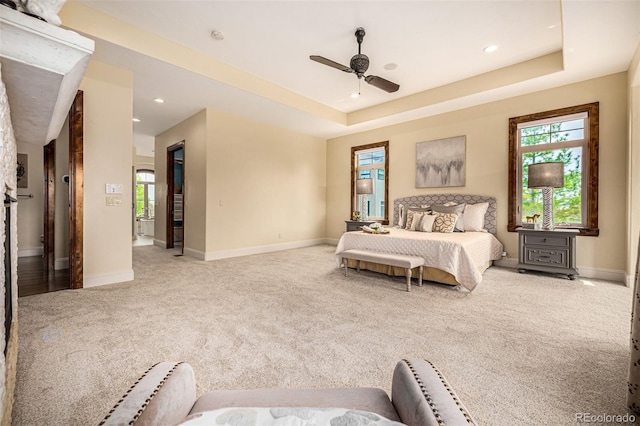 carpeted bedroom featuring ceiling fan and a tray ceiling