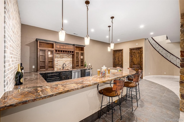 kitchen featuring kitchen peninsula, hanging light fixtures, tile flooring, sink, and a breakfast bar