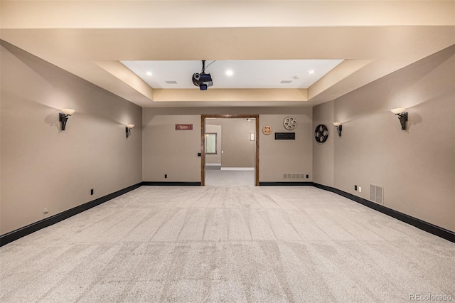 empty room with light colored carpet and a raised ceiling