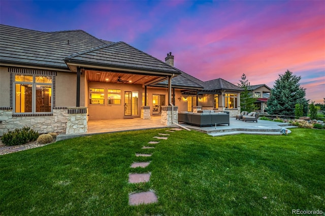 back house at dusk featuring an outdoor living space, a yard, and a patio area