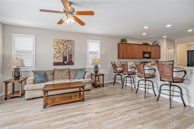 living room featuring ceiling fan and light hardwood / wood-style floors